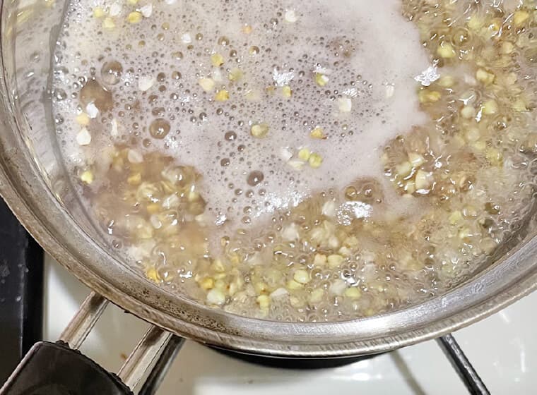 蕎⻨の実と⽔を鍋に⼊れ、沸騰したら弱⽕にして5分加熱する。